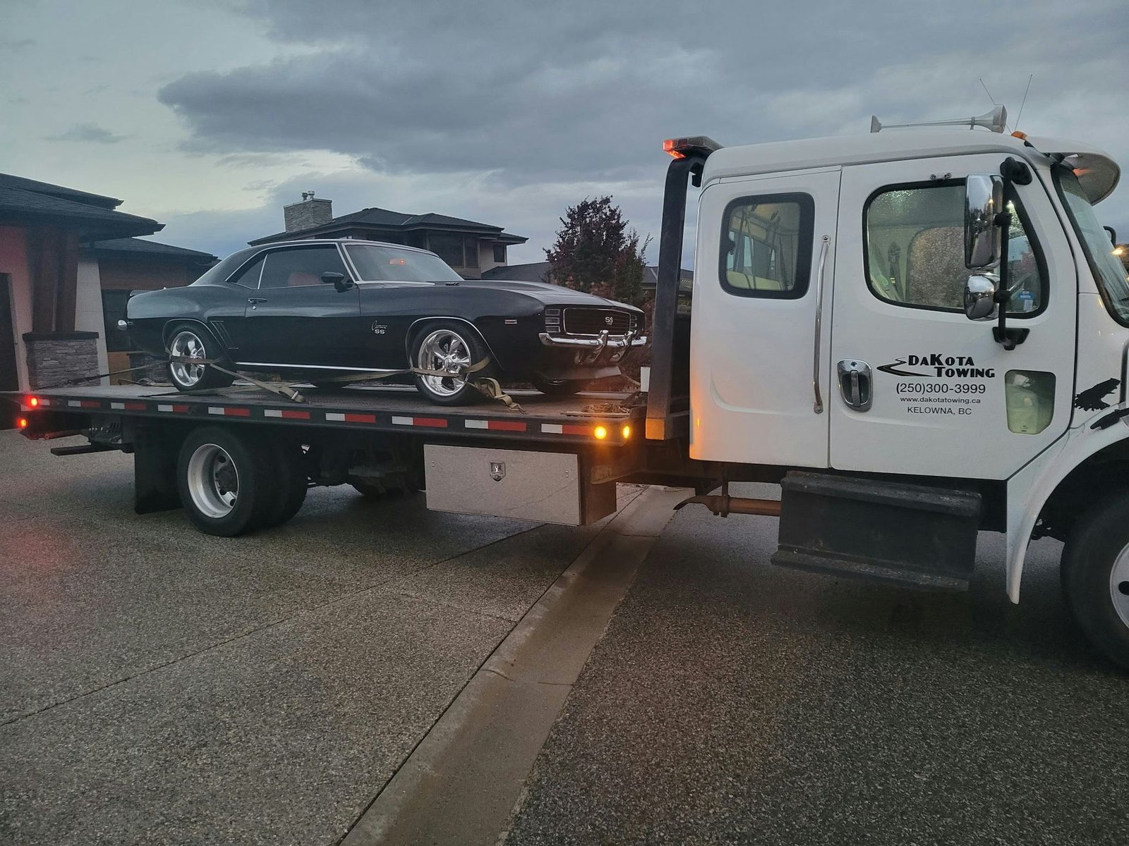 Classic black muscle car loaded on a flatbed tow truck