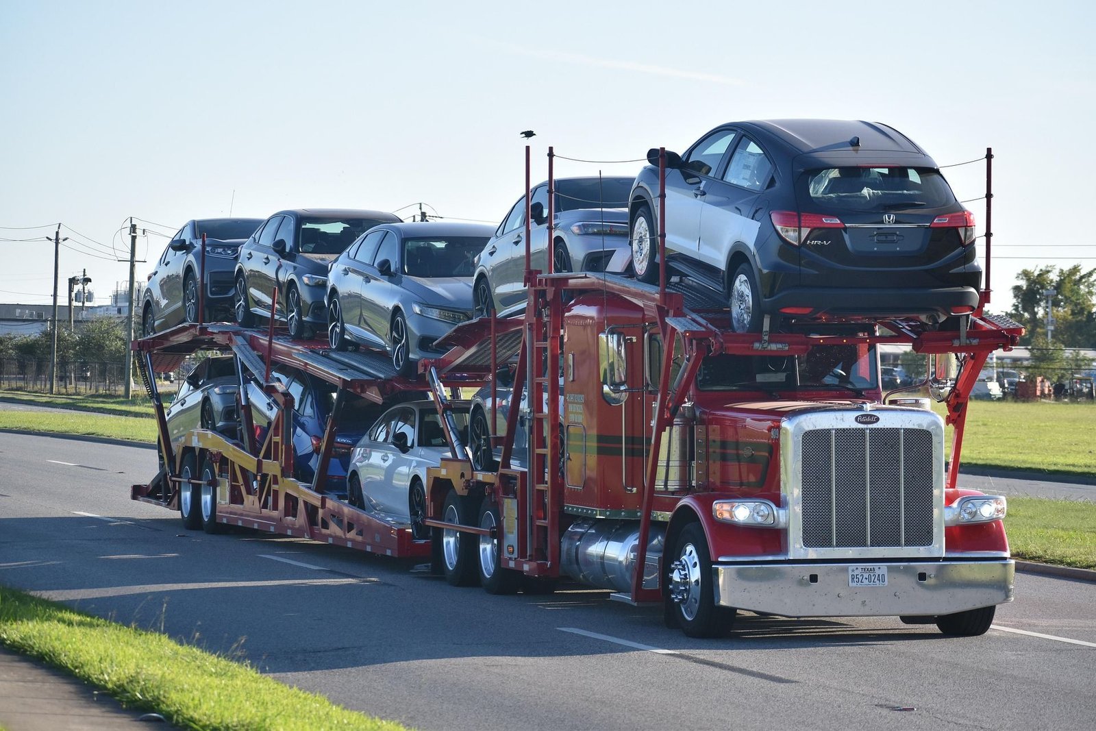 Car carrier truck loaded with multiple sedans and an SUV on a highway