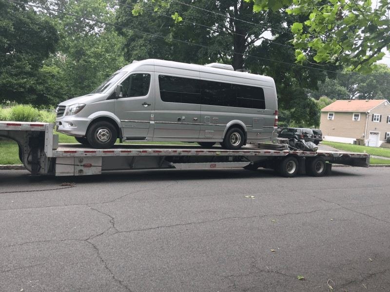 Camper van loaded on a flatbed transport trailer