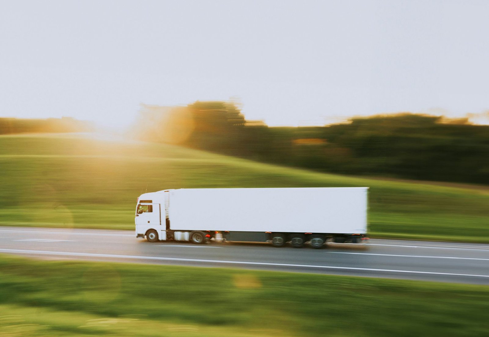 Truck driving down a sunlit country highway with motion blur